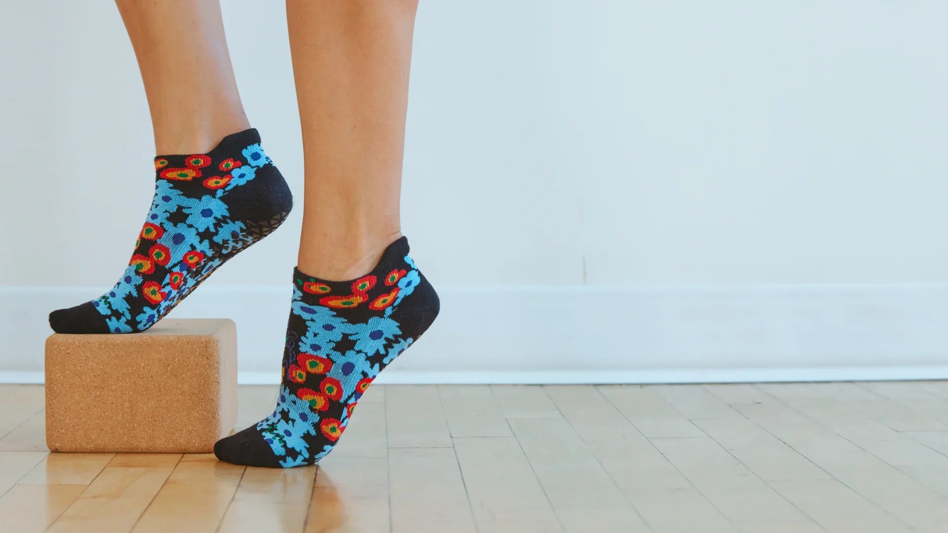Billede af fødder der bærer Garden Full Foot Grip Socks fra Pointe Studio samtidig med, at de balancere på en yoga blok