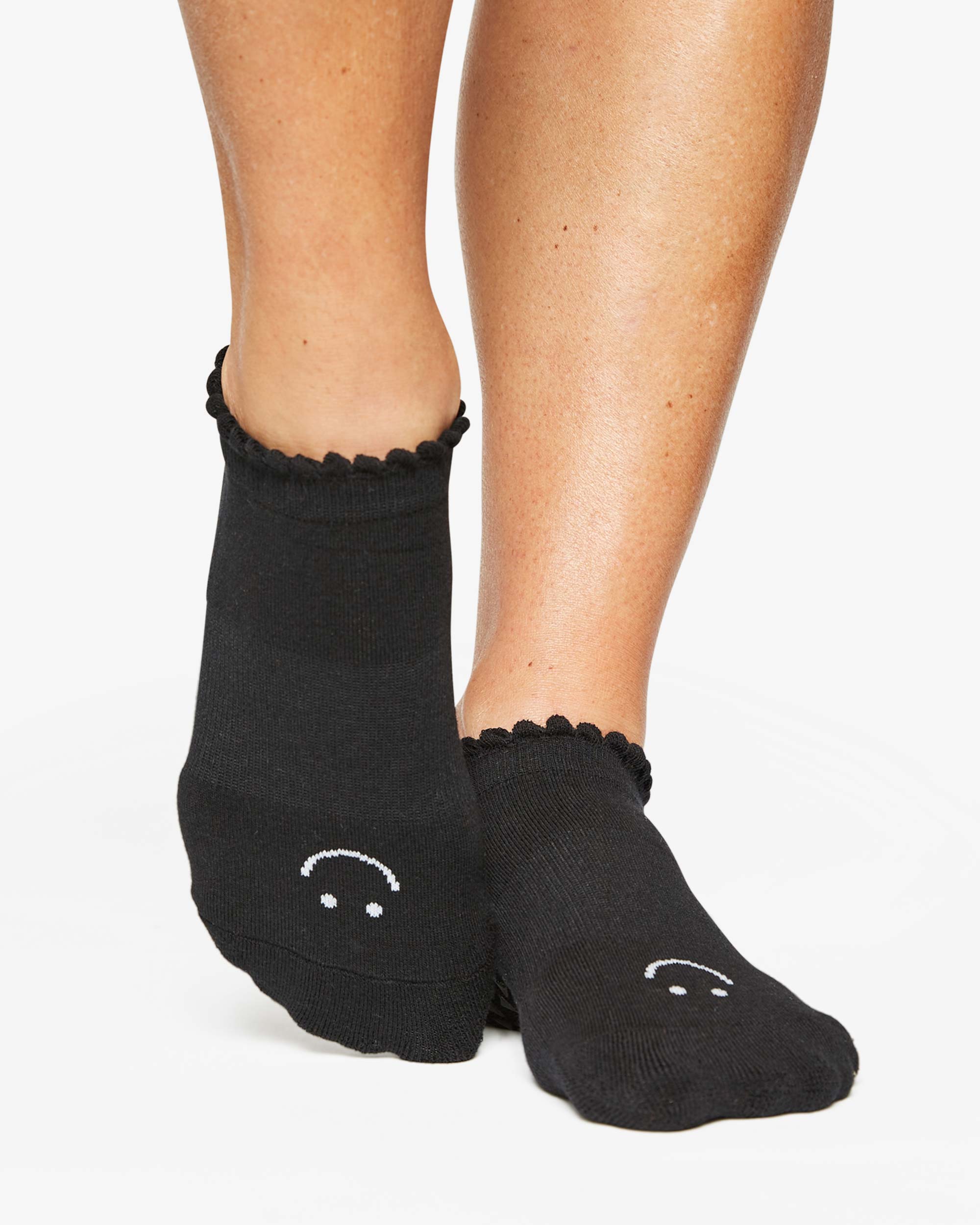 Close up photo of a woman's feet wearing black socks with a happy face on the top of the foot